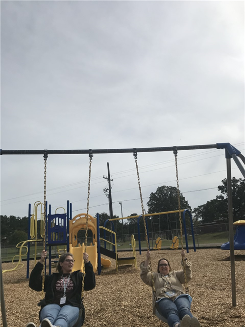 Ms Ratcliffe and Mrs. Sawin swinging on the playground 